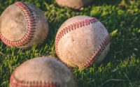close up photography of four baseballs on green lawn grasses